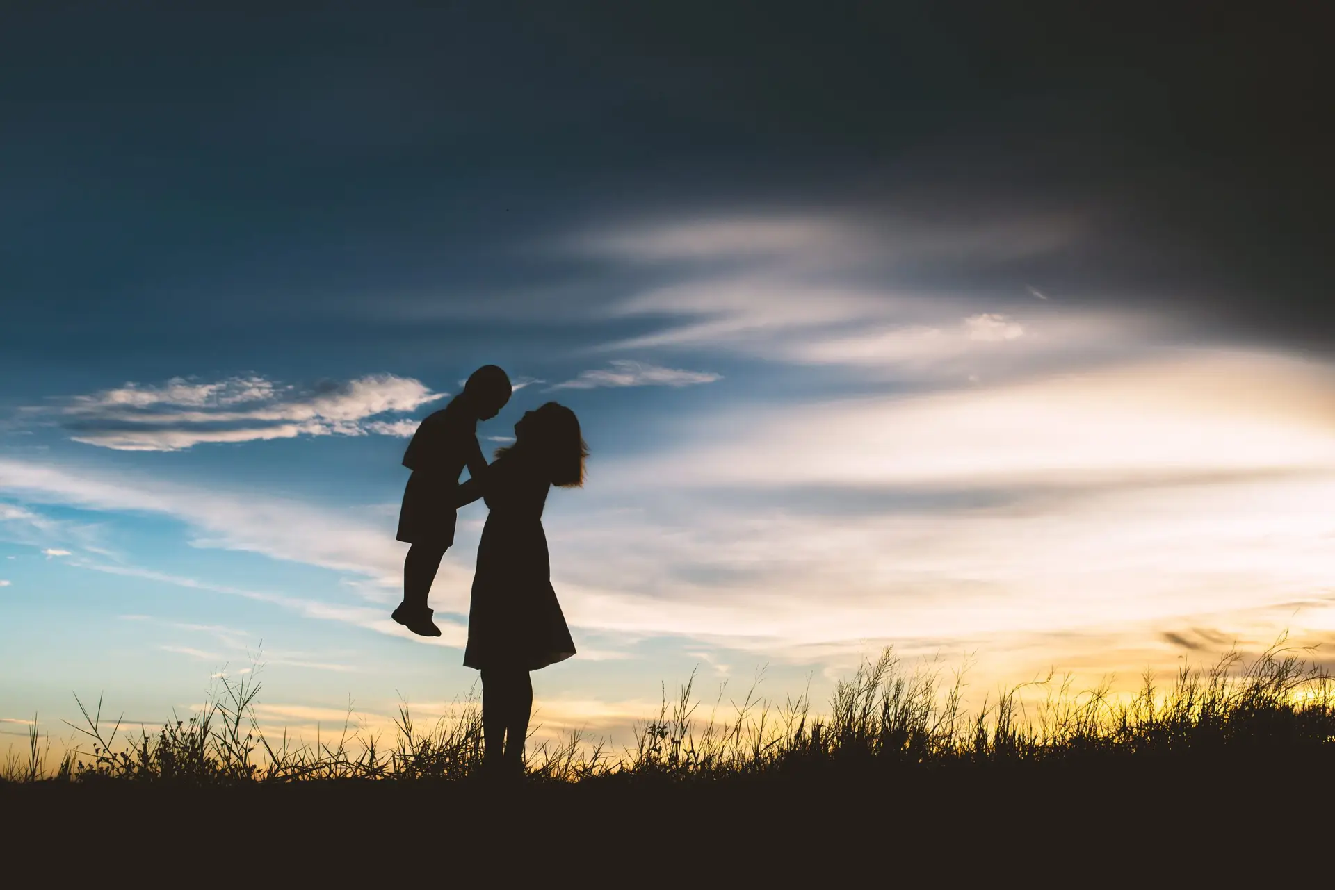 Mother encouraged her son outdoors at sunset, silhouette concept
