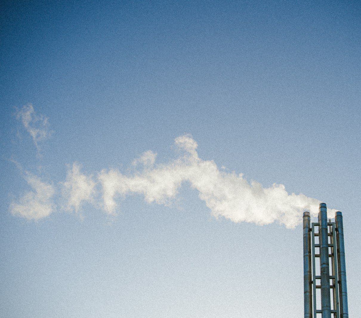 A metal chimney releasing white smoke into the sky