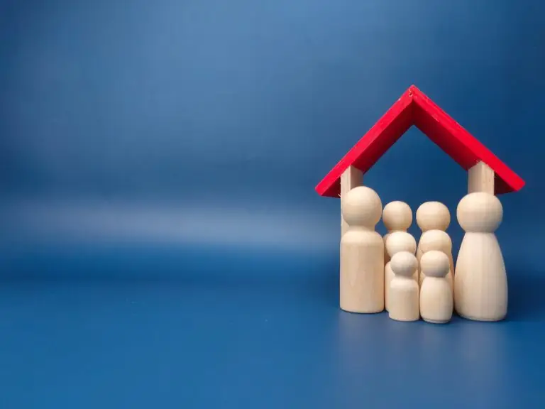 A family wooden doll with wooden house on a blue background with copy space